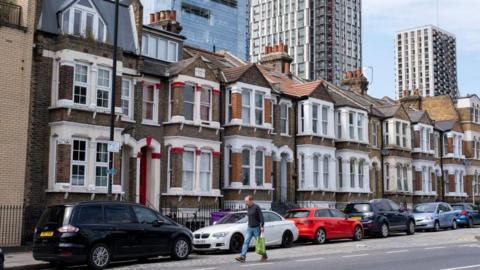 Terrace of low-rise homes with high-rise block towers behind in Tower Hamlets