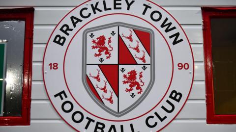 A photo of Brackley Town's club badge on a white wall