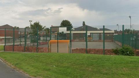 A down-trodden multi-use games area in Ribbleton, Preston, on a cloudy day.