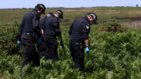 Police officers investigate the area near the home of 78-year-old former government minister Ann Widdecombe.