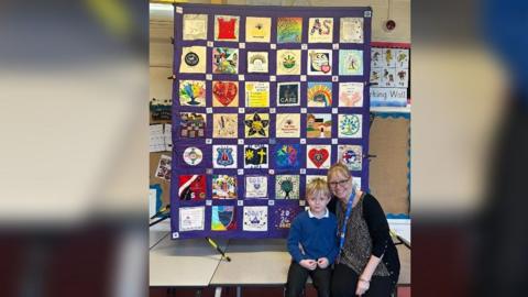 Paula Martin sat with a pupil in front of a quilted piece of art