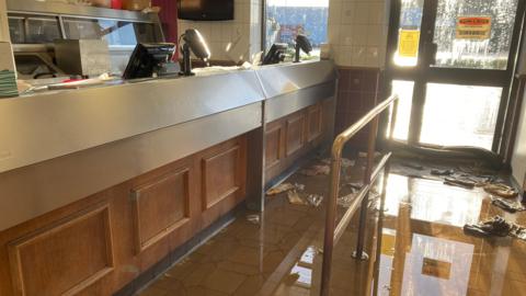 A flooded chip shop, there are sodden rags all over the floor