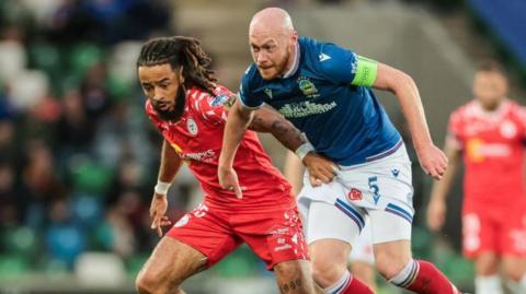 Shelbourne's Milan Mbeng contends for possession with Linfield's Chris Shields