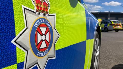 The side of a Wiltshire Police car. It is a close-up photo that shows the force's logo.