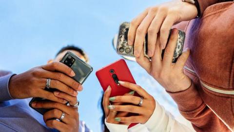 Low angle view of three young people using mobile phones outdoors.