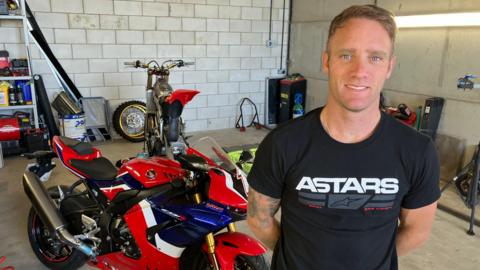 Tommy Bridwell in a garage with his bike behind him