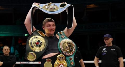 Lauren Price holds her world title belts in the ring