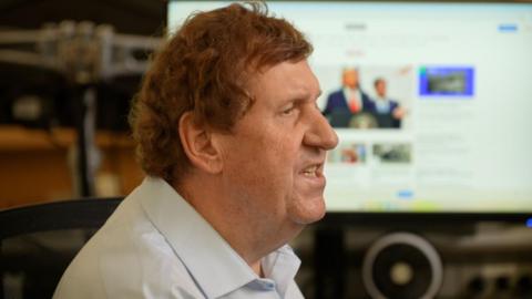 Gary O'Donoghue in the BBC's DC newsroom, with a computer behind him showing the BBC website