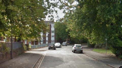 Wesley Road is pictured. It is a tree-lined street with a block of flats visible in the background