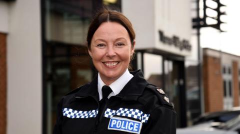 Retired Ch Supt Emma Garside stood outside a building with her uniform on and smiling at the camera.