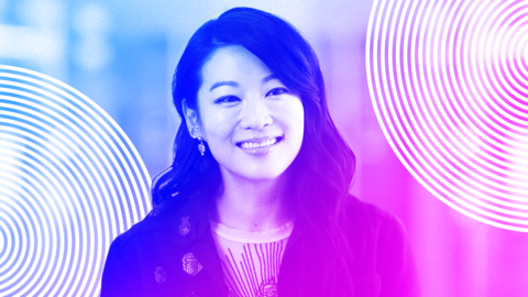 Headshot of Arden Cho smiling. She has long, wavy, dark brown hair and is wearing several gold, jewelled earrings. She is wearing a sheer cream top with brown embroidery and a brown jacket with gold brooches. The image is treated with a purple and blue wash and has concentric circles in the bottom left and top right corners - the branding for BBC Global Women.