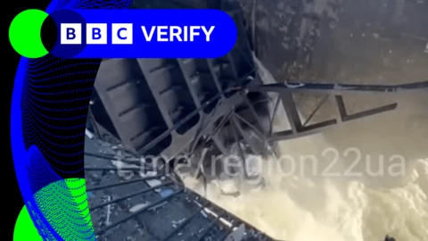 A breach in a dam with a large amount of water pouring out of it