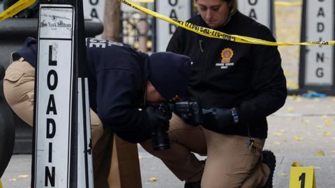 A member of the NYPD Crime Scene Unit takes a picture of a shell casing found at the scene where the CEO of UnitedHealthcare Brian Thompson was reportedly shot and killed in Midtown Manhattan, in New York City, U.S., December 4, 2024. REUTERS/Shannon Stapleton
