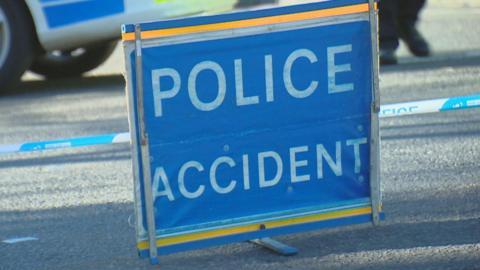 Police accident sign, bold white letters in a blue sign, on a road.