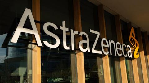 AstraZeneca sign with company name and logo on windows of a building with wooden columns