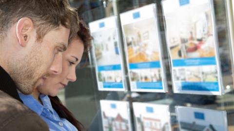 Young man and woman look in an estate agent's window 