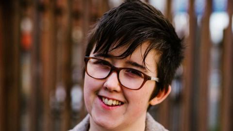 Shows a young girl with short hair and glasses smiling