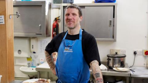 Jason Williamson, from the band Sleaford Mods, stood in a kitchen canteen.