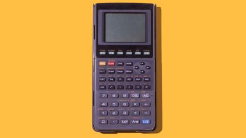 A calculator in front of a yellow background.