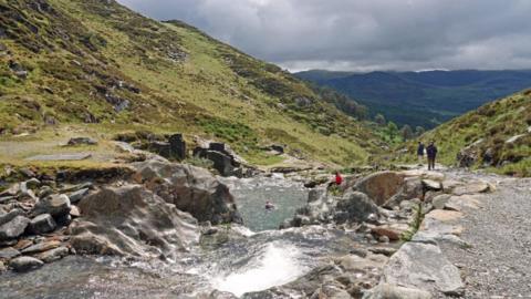 Pools on the Watkin Path, leading to summit of Snowdon. There are people swimming in the pools