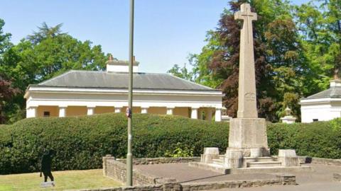 A stone war memorial with a cross at the top. 