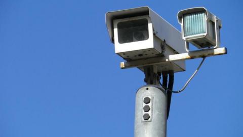 A CCTV camera high up, the sky is bright blue in the background.