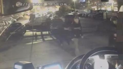 A grainy image of people walking to a bus 