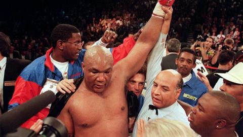 George Foreman has his hand raised by the referee