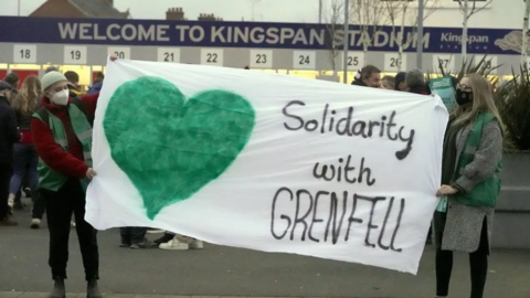 Protesters outside Kingspan stadium holding a solidarity with grenfell banner