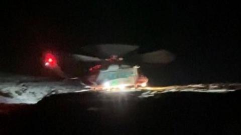 A helicopter at night on a snowy mountain 