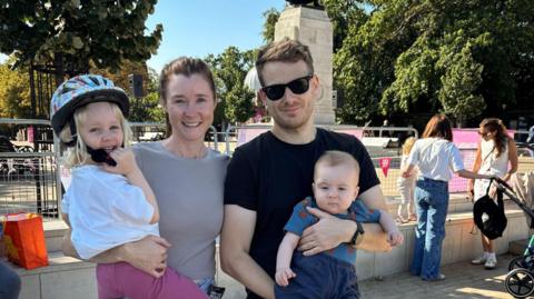 A man and a woman holding two young children and smiling.