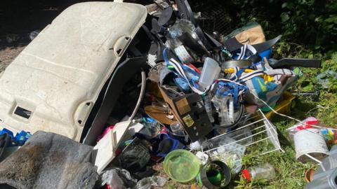 Fly-tipped rubbish including household items.