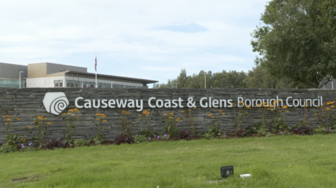 The stone wall outside Causeway coast and Glens council with the logo and words on it in metal.