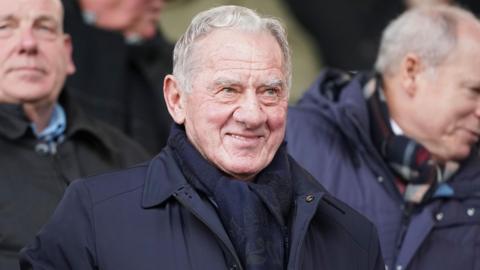 A grey-haired Milan Mandaric pictured wearing a dark coat while attending a football match