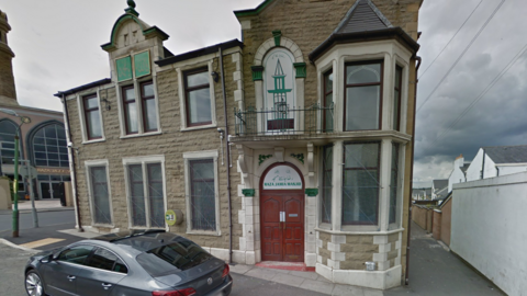 A street view image of the mosque. There is a car on the pavement outside.