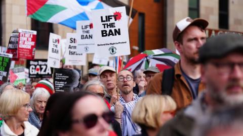 Pro-Palestine protesters in Edinburgh with signs held up in the air saying "Lift the Ban" 