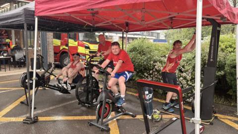 Members of Bingley Red Watch. One is on an exercise bike, one is on a rowing machine, and a third is on a different piece of gym equipment. 