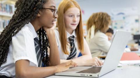 Two school pupils looking at a laptop.