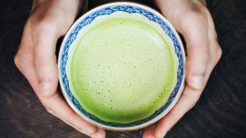 Two hands hold a cup of matcha.