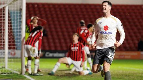 MK Dons goalscorer Jon Mellish celebrates as Walsall players in the background look exasperated