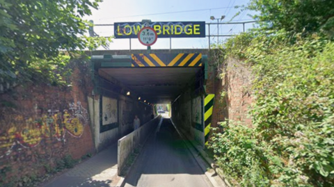 A view of the Cow Lane Underpass on a sunny day. A sign Low Bridge stands over it.