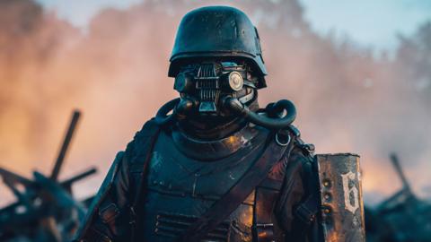 A soldier dressed in heavy armour. His face is covered by a Steampunk-style mask