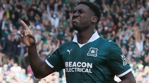 Bim Pepple wearing a green and white Plymouth Argyle shirt, is in action for the club.