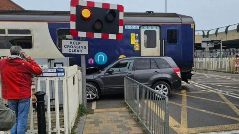 A damaged car alongside a train on a level crossing in Redcar