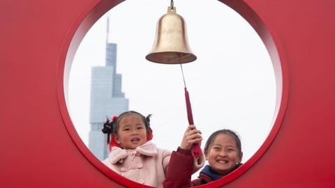 Two young girls ring the New Year bell on the city wall of Nanjing on the first day of the Chinese Lunar New Year in Nanjing, China, on February 17, 2026.