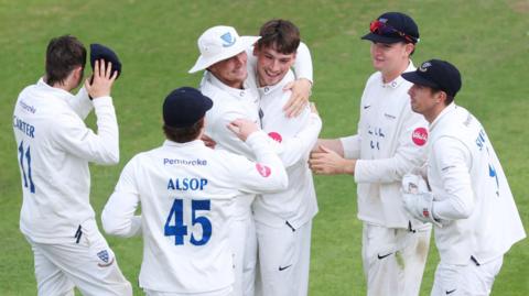 Sussex bowler Henry Crocombe is mobbed by his team-mates in celebration