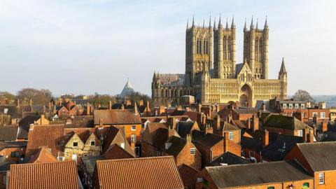 View of Lincoln Cathedral taken from the nearby castle walls. There are red-bricked houses in the foreground.