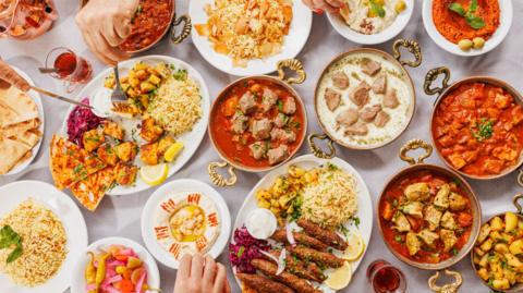The photo looks down on a table which is filled with different dishes in plates and bowls.