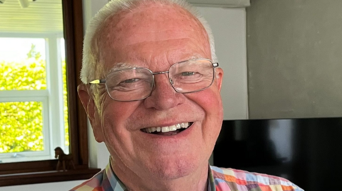 A smiling man who is wearing glasses.