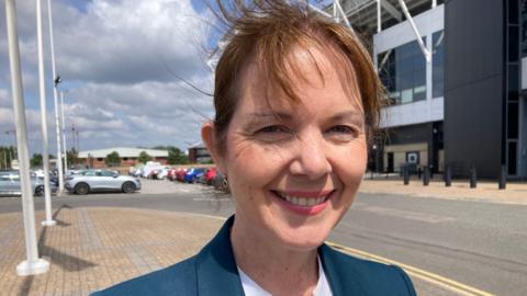 Claire Ward outside Pride Park. She is smiling and is wearing a green jacket. 